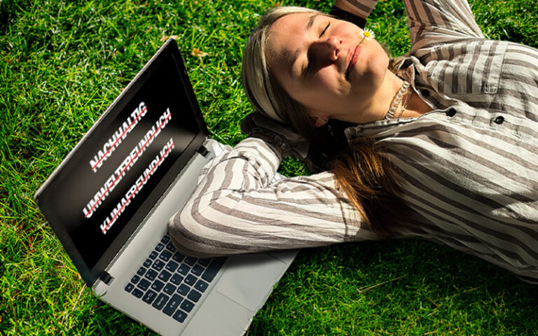 Frau liegt auf einer Wiese neben einem Laptop mit Begriffen rund um Nachhaltigkeit und Umweltfreundlichkeit.